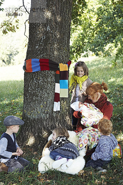 Mutter mit Kindern im Schatten an einem Baum