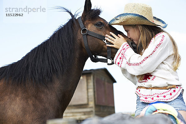 Mädchen mit Strohhut küssendes Pferd