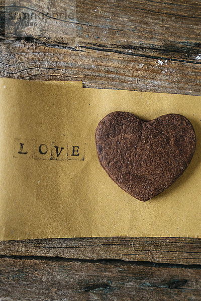 Herzförmiges Schokoladen-Mürbegebäck auf Papier mit dem Wort Liebe .