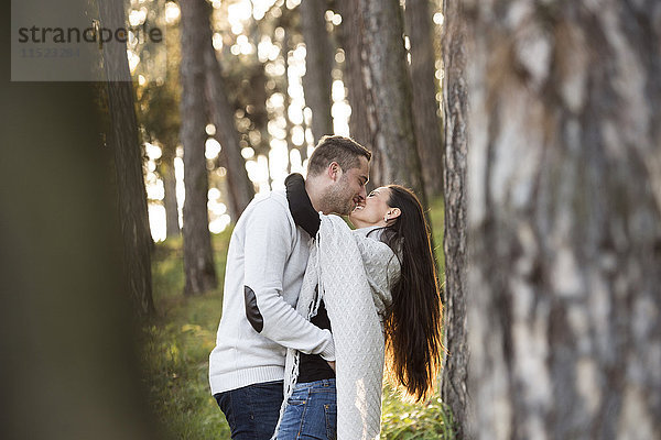 Glückliches Paar beim Küssen im Wald