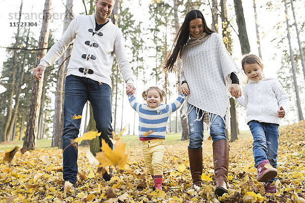 Glückliche Familie mit zwei Mädchen im Herbstlaub