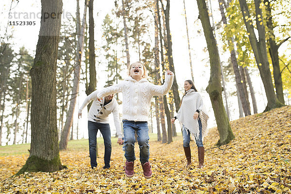 Glückliches Mädchen mit Familie im Herbstwald