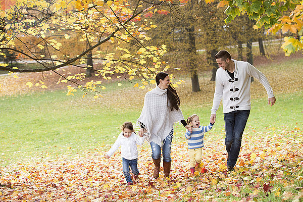 Glückliche Familie mit zwei Mädchen im Herbstlaub