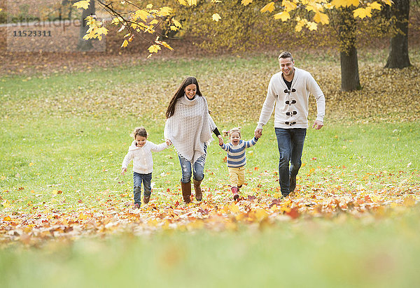 Glückliche Familie mit zwei Mädchen im Herbstlaub