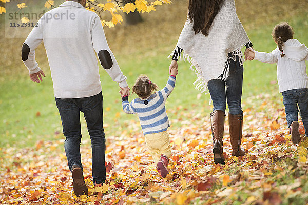 Glückliche Familie mit zwei Mädchen im Herbstlaub