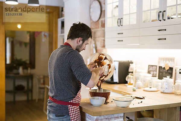 Mann steht in der Küche und backt Ringkuchen