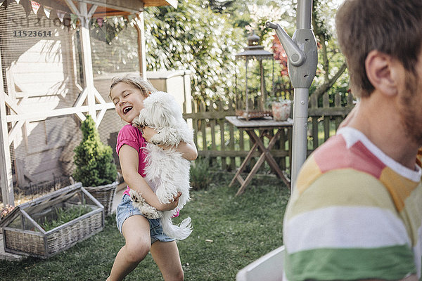 Mädchen spielt mit Hund im Garten