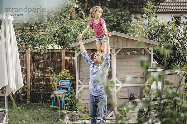 Vater trägt Tochter auf Schultern im Garten