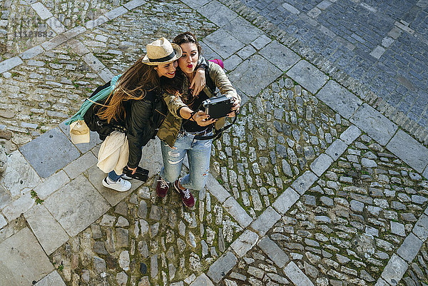 Zwei glückliche junge Frauen  die einen Selfie mit einer Kamera nehmen.