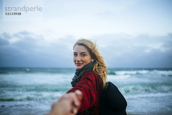 Junge Frau an der Hand eines Mannes am Strand