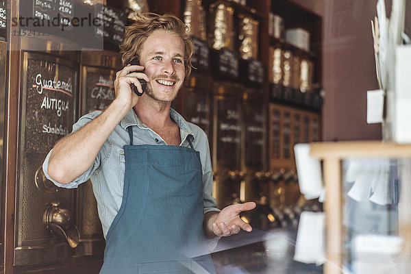 Lächelnder Kaffeeröster in seinem Laden am Telefon