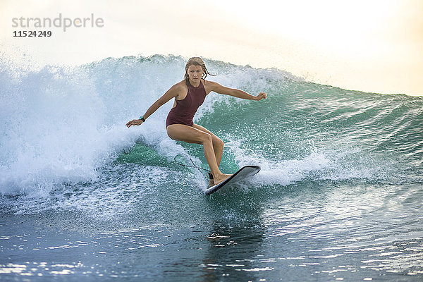 Indonesien  Bali  Frau beim Wellenreiten