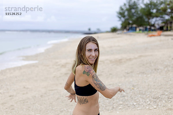 Indonesien  Bali  lächelnde Frau mit Tattoos am Strand