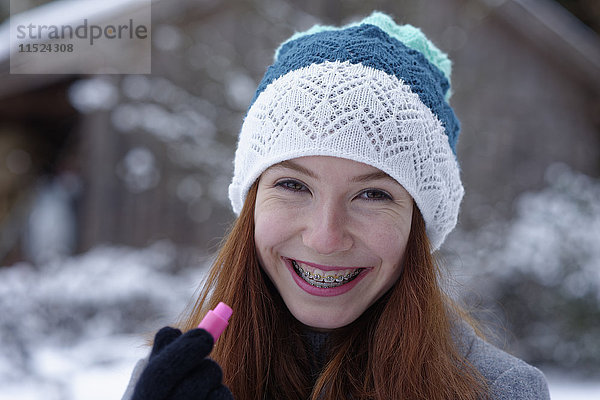 Porträt eines glücklichen Teenagers mit Lippenbalsam