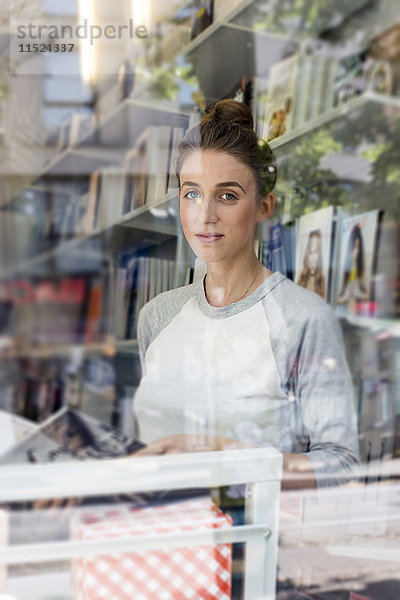 Junge Frau in einer Buchhandlung mit Blick durchs Fenster