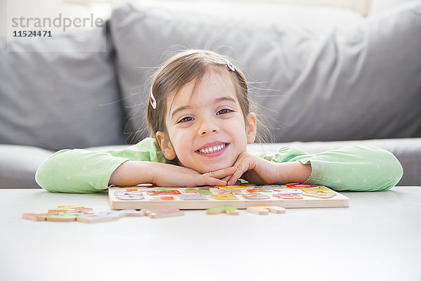 Porträt des lächelnden Mädchens mit Holzbuchstaben zu Hause
