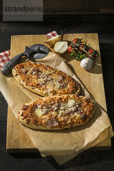 Zwei Pizzabrote mit Tomaten  Zwiebeln  Salami und Käse