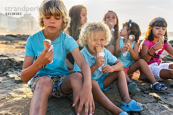 Gruppe von sechs Kindern beim Eis essen am Strand