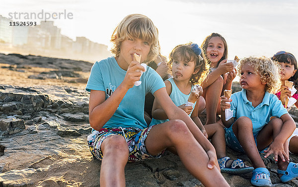Gruppe von sechs Kindern beim Eis essen am Strand
