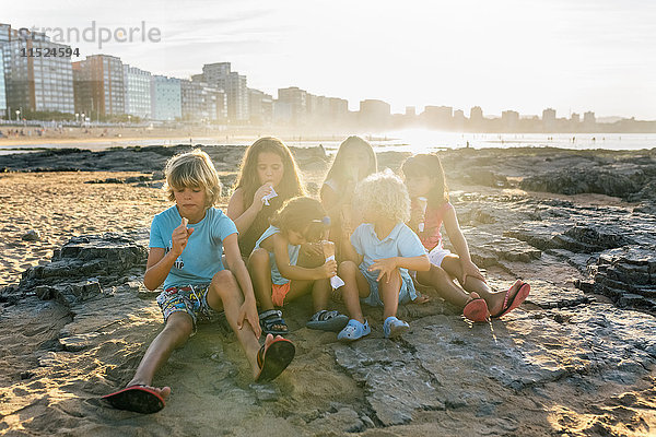 Gruppe von sechs Kindern beim Eis essen am Strand