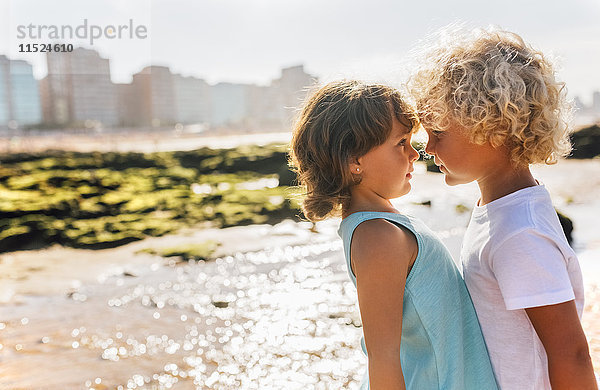 Kleiner Junge und Mädchen von Angesicht zu Angesicht am Strand