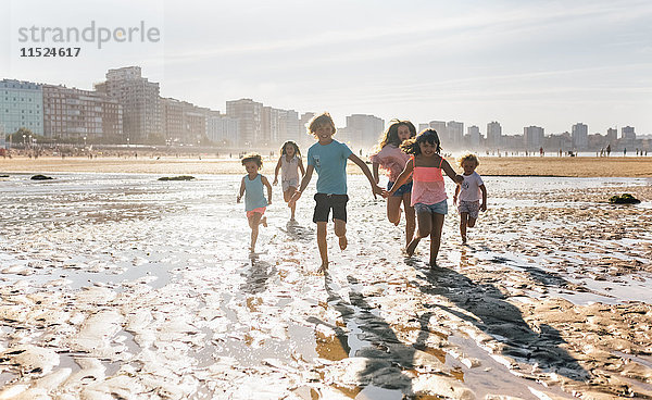 Gruppe von sechs Kindern beim gemeinsamen Laufen am Strand