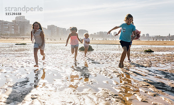 Gruppe von fünf Kindern beim gemeinsamen Laufen am Strand