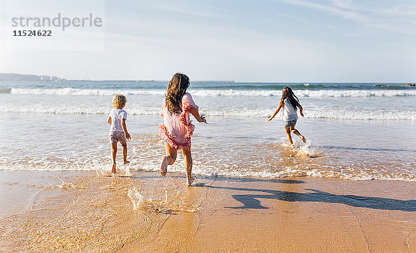 Rückansicht von drei ins Meer rennenden Kindern