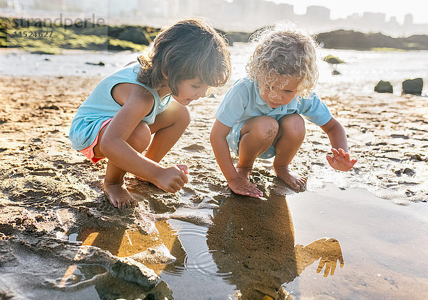 Kleiner Junge und Mädchen spielen zusammen am Strand.