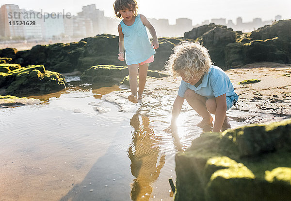 Kleiner Junge und Mädchen spielen zusammen am Strand.