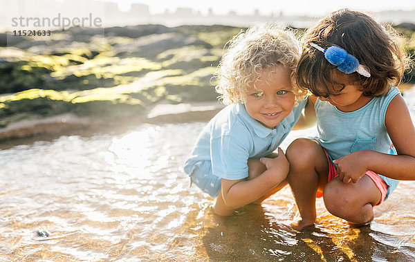 Kleiner Junge und Mädchen spielen zusammen am Strand.