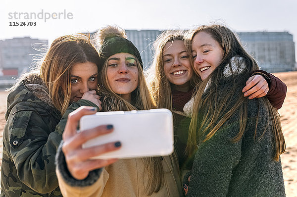 Vier Freunde  die Selfie mit Handy am Strand mitnehmen