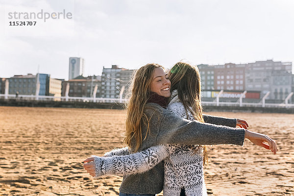 Zwei Freunde  die sich am Strand umarmen.