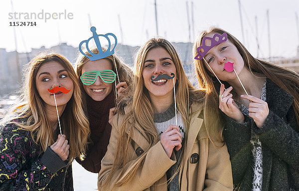 Gruppenbild von vier Freunden mit Spielzeugschnurrbart  Sonnenbrille und Krone