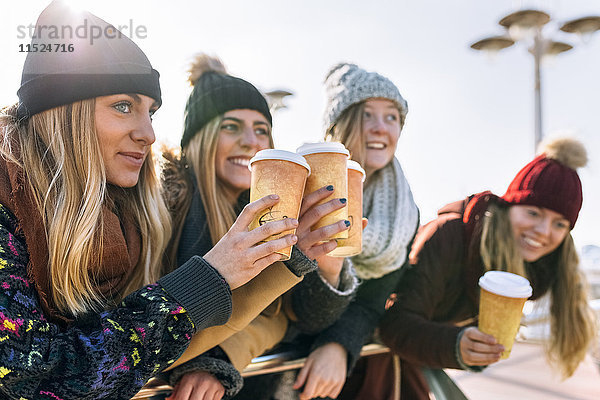 Vier Freunde  die im Winter mit Kaffee anstoßen.