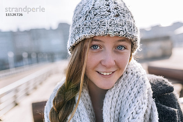 Porträt eines lächelnden Teenagermädchens mit Wollmütze und Schal