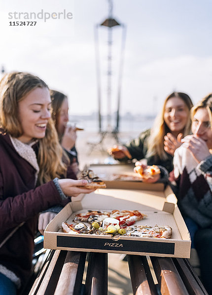 Vier Freunde beim Pizzaessen im Freien