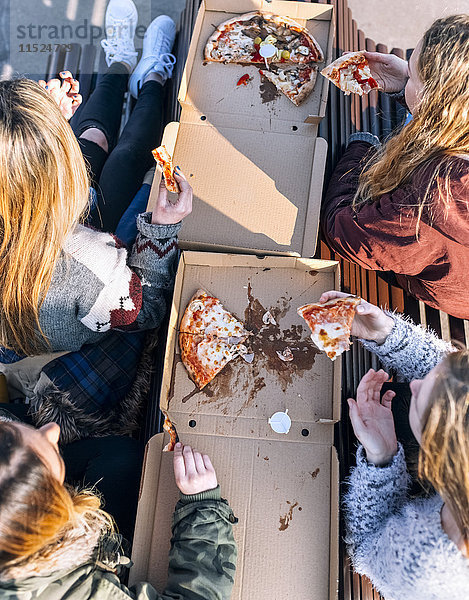 Vier Freunde beim Pizzaessen im Freien