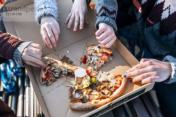 Vier Freunde essen Pizza im Freien  Teilansicht