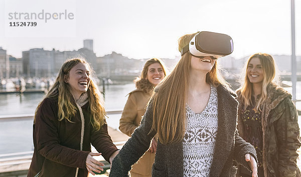 Teenager-Mädchen  das eine VR-Brille trägt  während ihre Freunde sie beobachten.