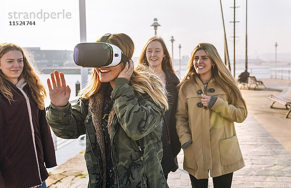 Teenager-Mädchen  das eine VR-Brille trägt  während ihre Freunde sie beobachten.