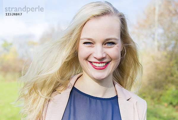 Porträt einer lächelnden jungen blonden Frau im Freien