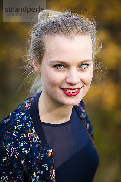 Porträt einer lächelnden jungen Frau im Herbst
