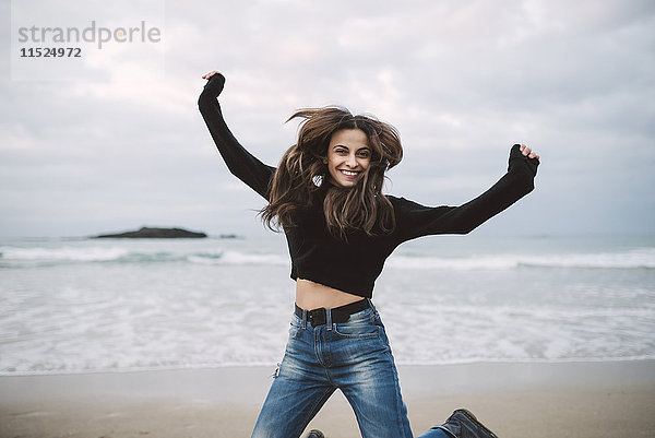 Fröhliche junge Frau beim Springen am Strand
