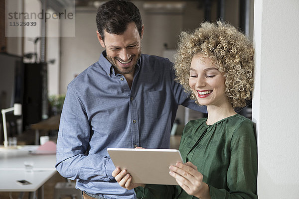 Lächelnder Mann und Frau beim Betrachten der Tablette im Büro