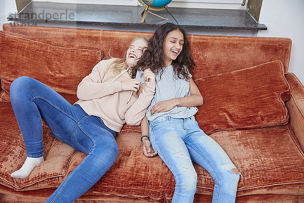 Zwei lachende Mädchen entspannen sich auf der Couch