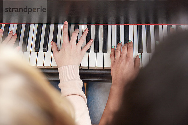 Nahaufnahme von zwei Mädchen  die zusammen Klavier spielen