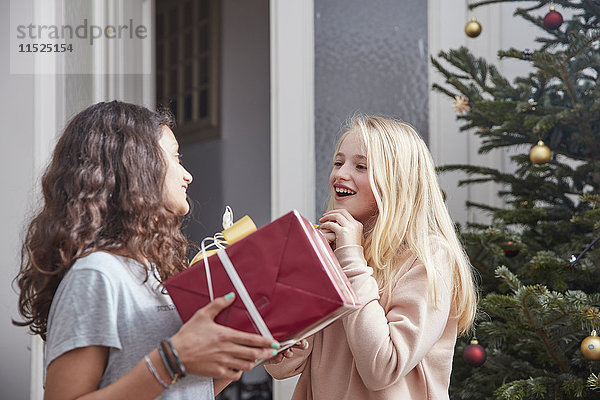 Mädchen übergibt Weihnachtsgeschenk an Freundin