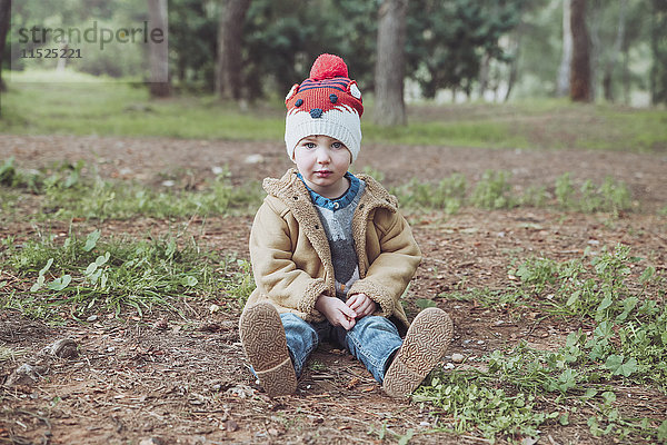 Portrait eines Jungen mit Wollmütze sitzend inforest