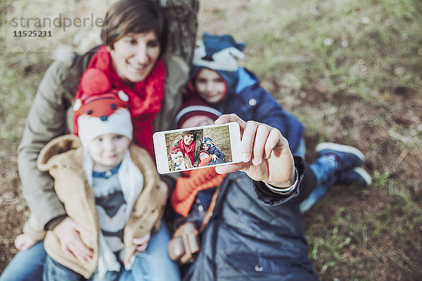 Familie  die ein Selfie mit Smartphone im Wald nimmt